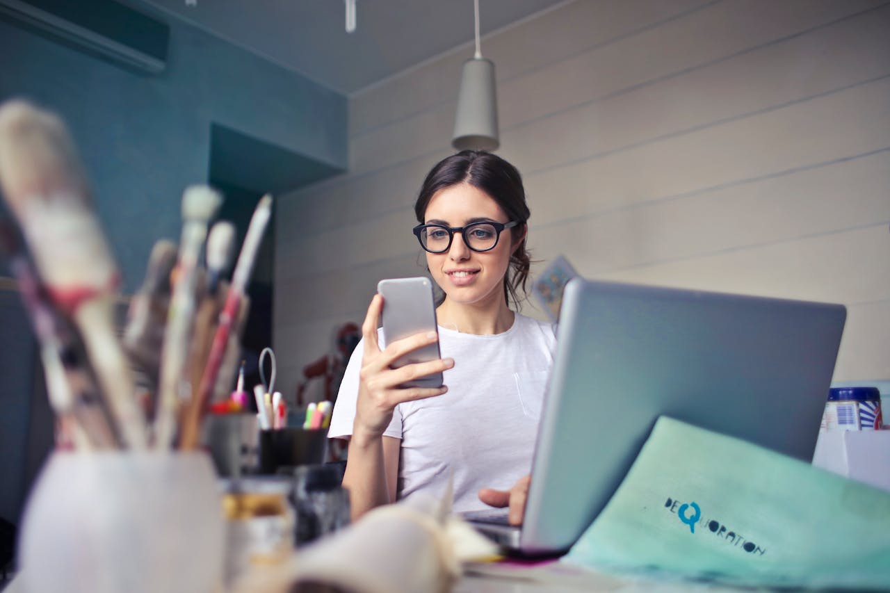 Künstlerin arbeitet im Büro Smartphone Laptop Bürojob für Kreative geeignet Vor- und Nachteile