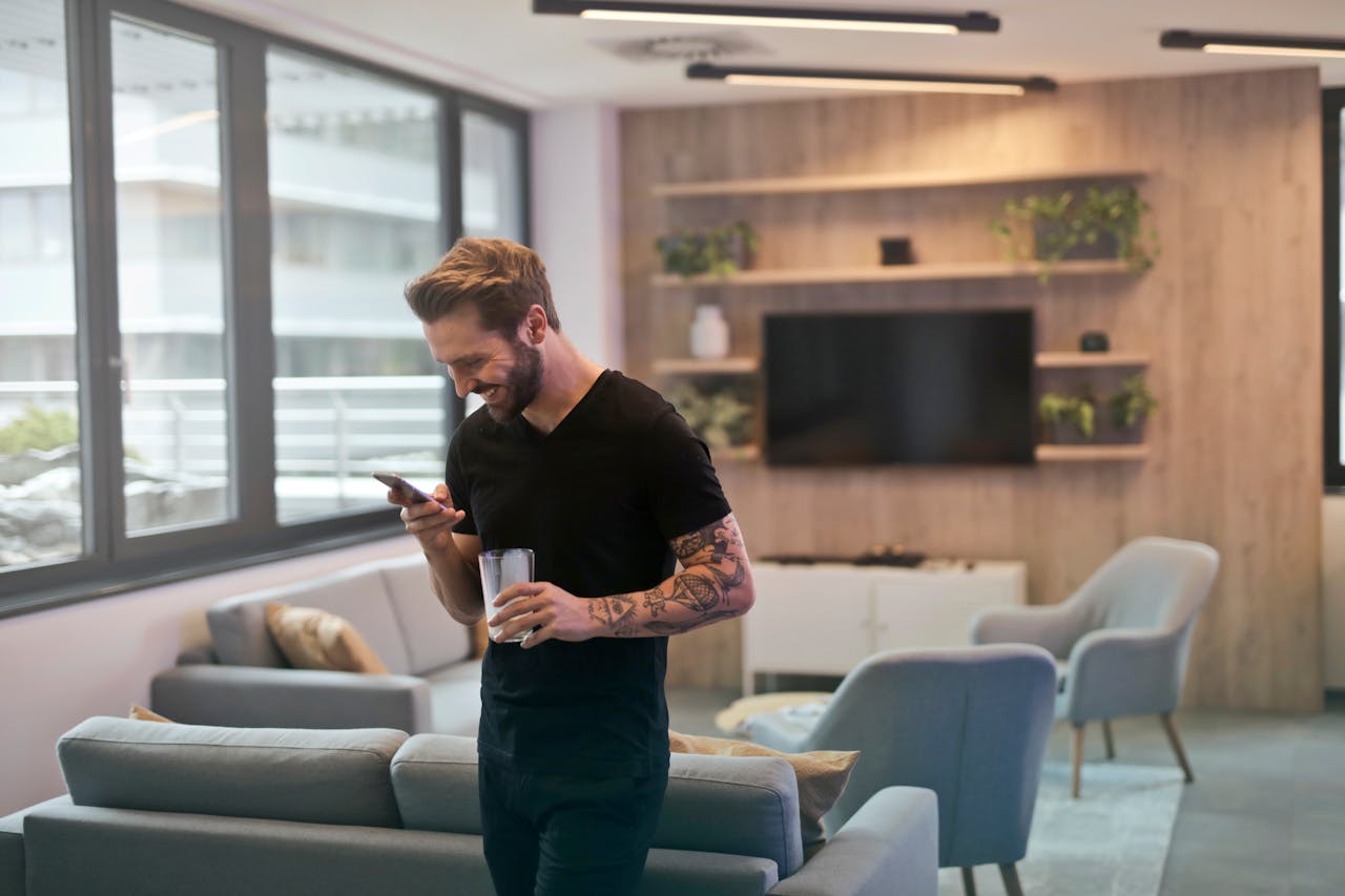 Mann Künstler Tattoos blickt auf Smartphone WhatsApp-Marketing für Künstler Darum lohnt es sich